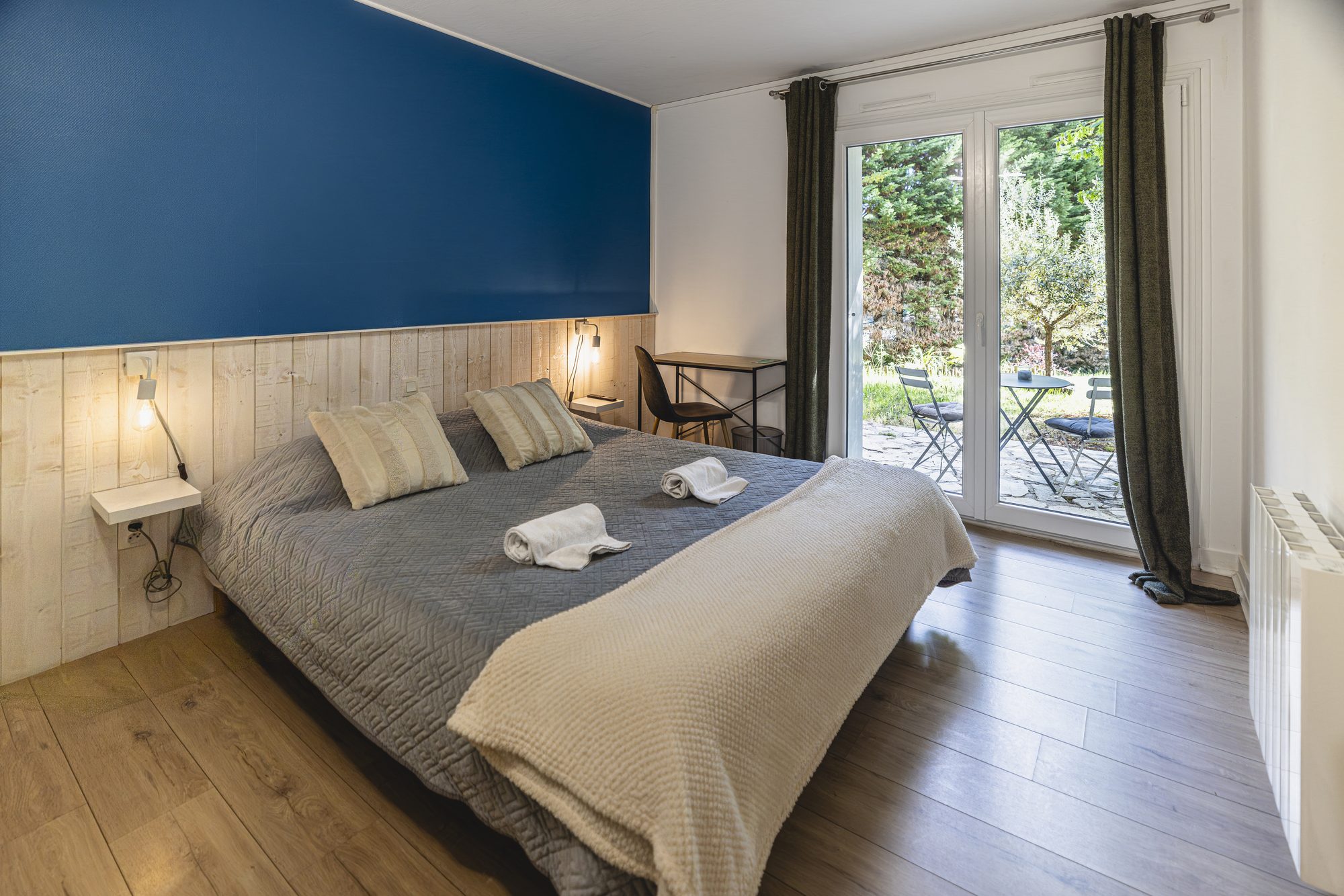 Chambre double, mur bleu et porte-fenêtre sur le jardin
