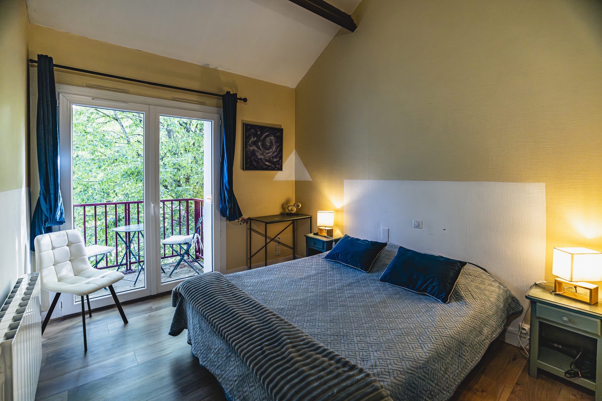 Chambre double aux murs ocre, avec balcon et petite table